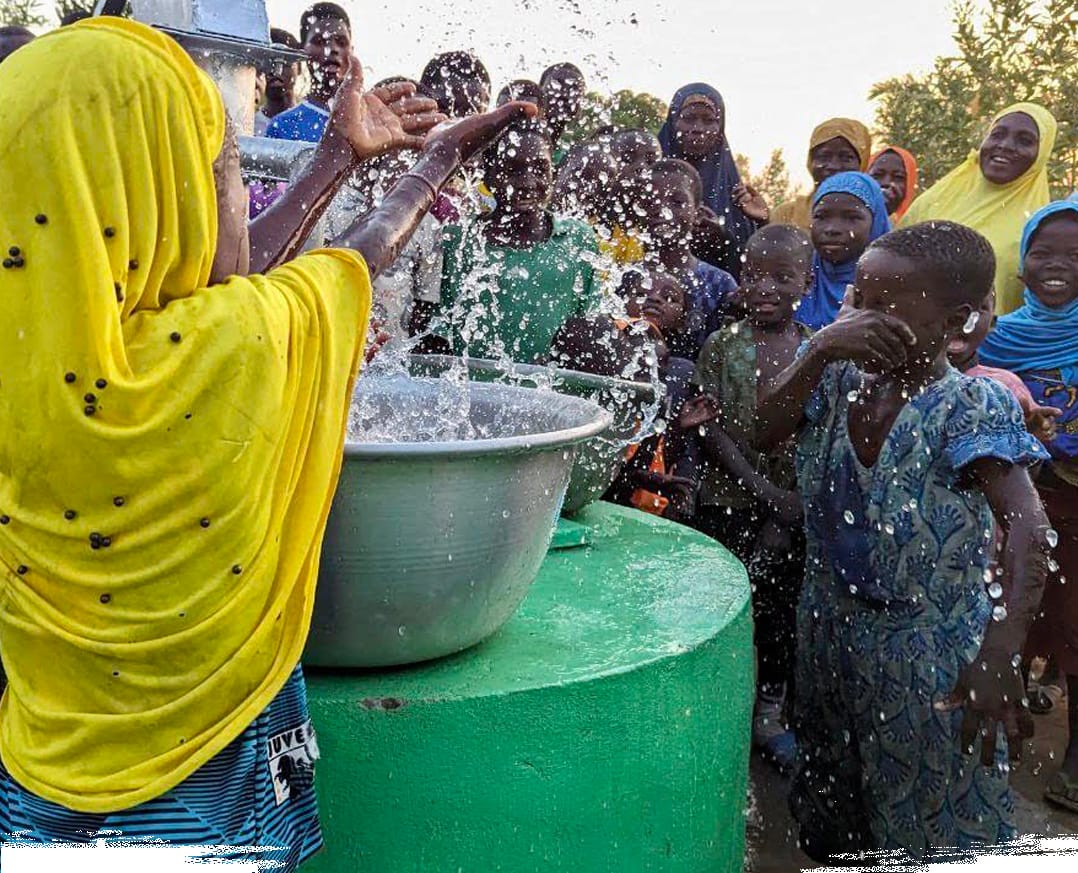 "Happy children splashing water from a Ramadan well in Africa"