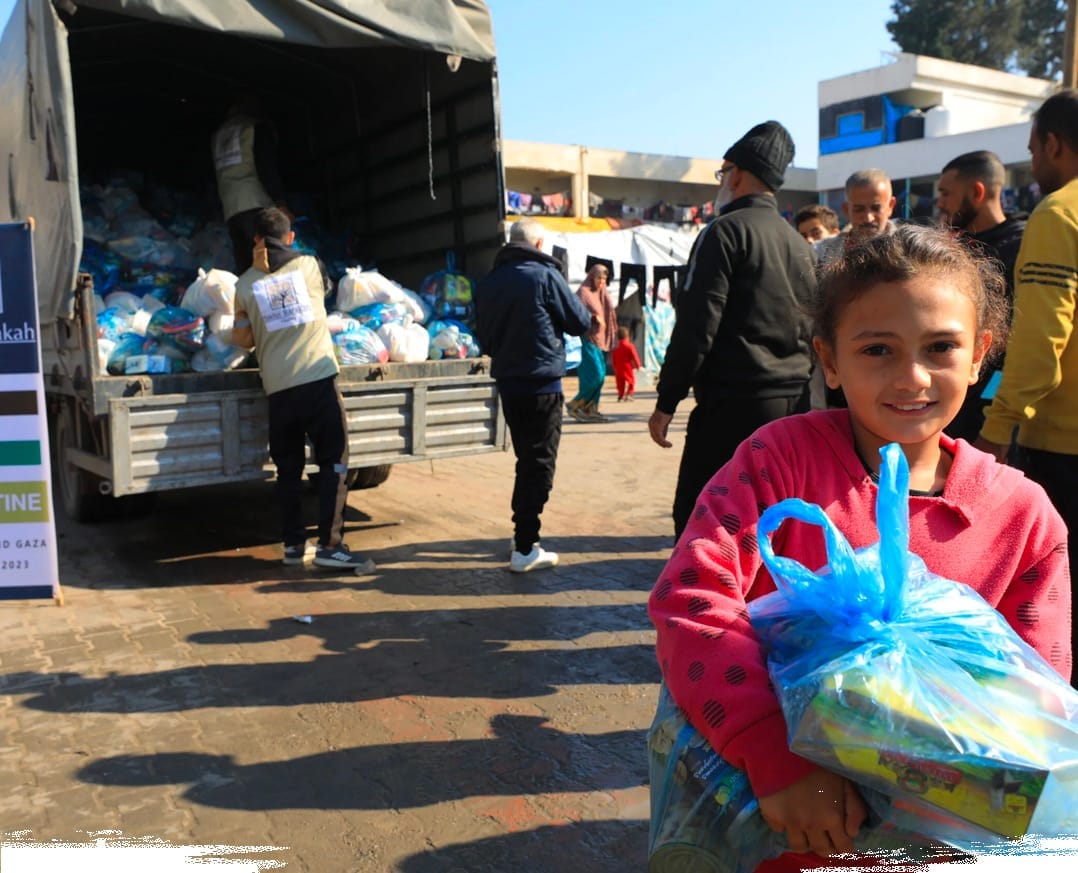 A young girl receiving a relief package: your donations for children in Palestine provide vital emergency support and food for families in need.